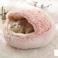 Pink fluffy pet bed with a small cat inside on a white background